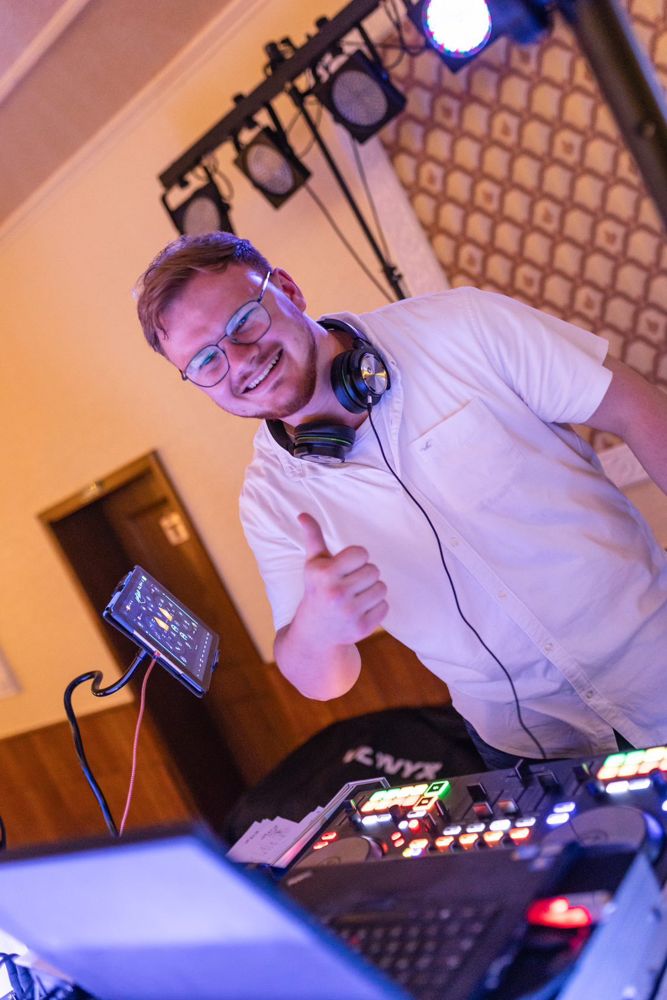 Leon am DJ-Pult, lacht und zeigt Daumen hoch
